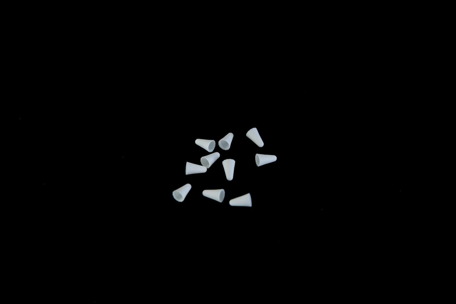 Home 3 Minimalistic image of white earplugs scattered on a black background with copy space.